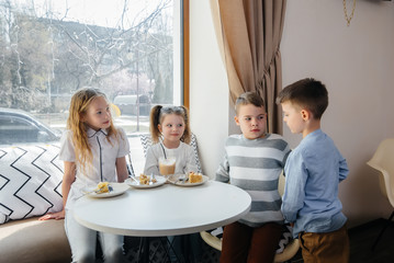 A large friendly company of children celebrate the holiday in a cafe with a delicious dessert. The day of the birth
