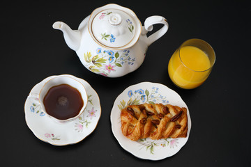 Continental breakfast with a teapot on a black table