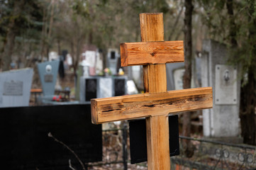 new wooden cross with a sign on the grave in the cemetery. Christian funeral of relatives.