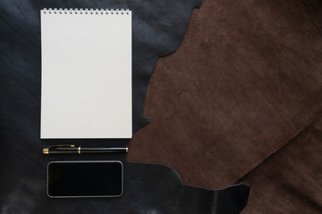Flat lay - Notepad, phone and pen on a leather background. workplace concept. copy space