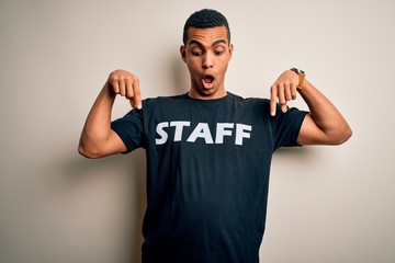Young handsome african american worker man wearing staff uniform over white background Pointing down with fingers showing advertisement, surprised face and open mouth