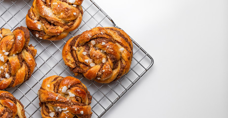 Aerial view of several homemade baked Swedish cinnamon rolls or kanelbulle on a cooling rack. White...