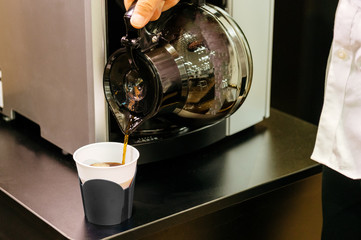 コーヒーポットからコーヒーを注ぐシーン　オフィスの仕事中のコーヒーブレイク