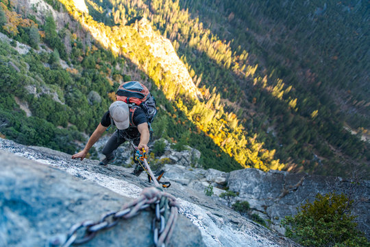 Man with hat looking down jugging rope up with backpack on El Capitan