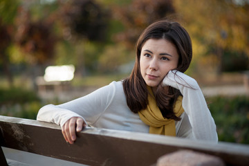 beautiful brunette girl resting in the autumn in the park on a b