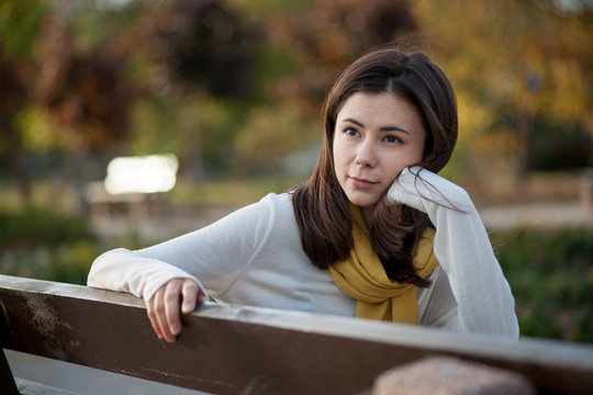 beautiful brunette girl resting in the autumn in the park on a b