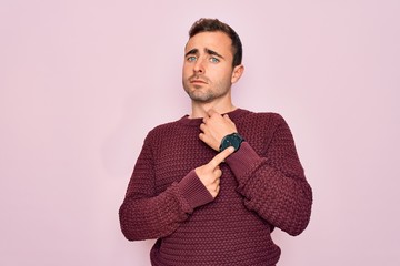 Young handsome man with blue eyes wearing casual sweater standing over pink background In hurry...