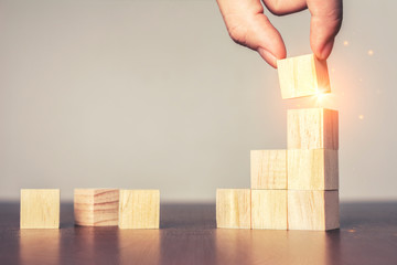 Hand arranging wood block stacking as step stair on table.New normal Business development Decide...