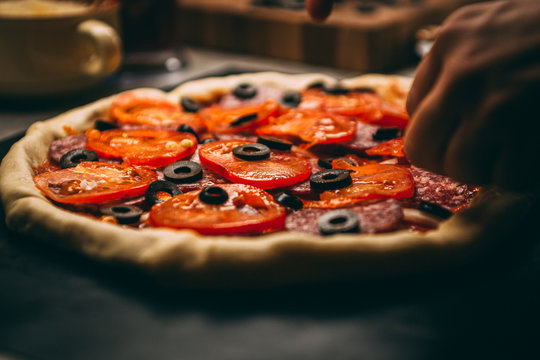Closeup hand of chef baker in white uniform making pizza at kitchen