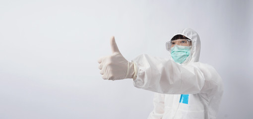 Wide angle images of Asian woman doctor in PPE suit or personal protection equipment and medical goggles, mask, gloves and showing thumb up or like it symbolic which represent happy moment