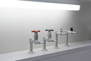 four different colored fluid taps in a laboratory