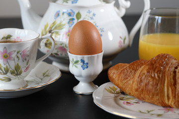 Continental breakfast with a teapot on a black table