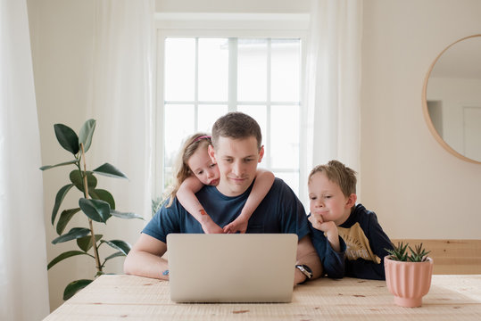 parent working from home with kids climbing on him