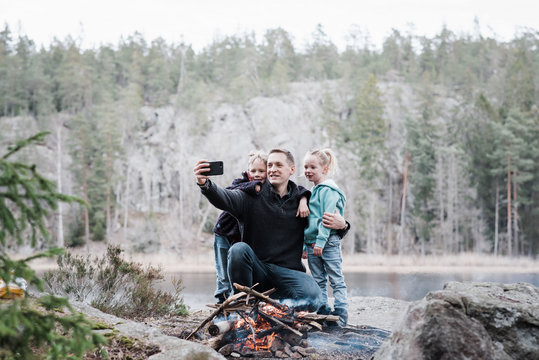 father taking pictures with his kids whilst enjoying a campfire