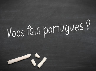 Portuguese text with the words Do you speak Portuguese? on a blackboard