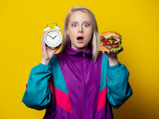 surprsied girl in 80s clothes style with burger and alarm clock