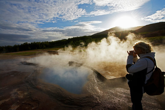 mature woman taking picture of geothermal pool in Iceland