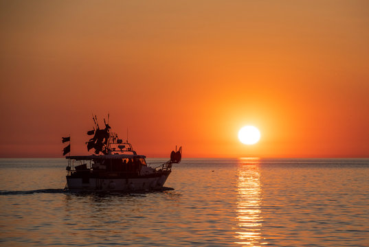 fishing boat sailing into sunset of the coast of Croatia