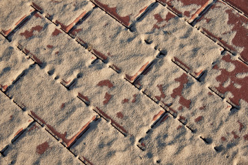 Paving slabs covered with sand in the rays of the setting sun. Background