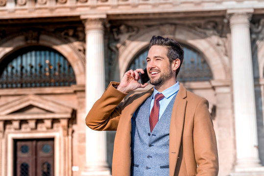 An elegant man on a square using his smartphone