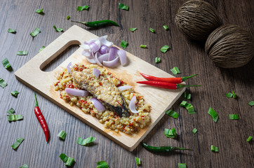 Steam salted King mackerel fish with minced garlic and chili salad on wooden background. ( Spicy Thai Food call Yum Pla Kem )