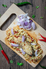 Steam salted King mackerel fish with minced garlic and chili salad on wooden background. top view. ( Spicy Thai Food call Yum Pla Kem )