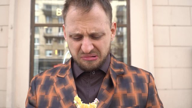 Portrait of a young man who eats a tasteless sandwich. the concept of disgusting food