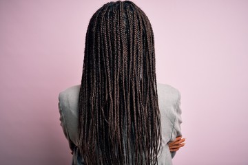 Young african american business woman standing over pink isolated background standing backwards looking away with crossed arms - Powered by Adobe
