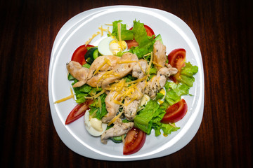Salad with chicken and vegetables in a white plate