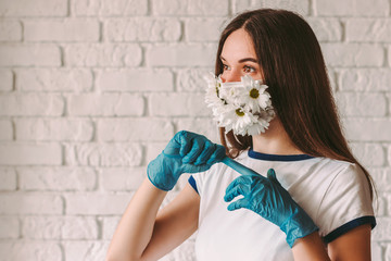 Portrait happy woman doctor in medical face mask with flowers taking off latex protective gloves. Beautiful girl in summer protective mask removing medical gloves. Win, end coronavirus COVID-19 fight