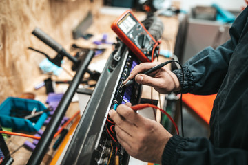 Man repairing electrical scooter in special workshop.