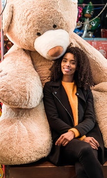 Happy Ethnic Woman Sitting With Giant Teddy Bear