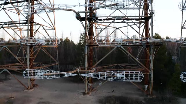 Drone flight over duga 3 radar antenna in the Chernobyl exclusion zone. Secret missile military area with sunset sun and surrounded by forest