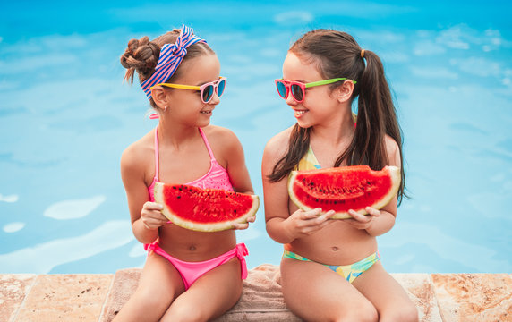Cheerful girls eating watermelon near pool - Powered by Adobe