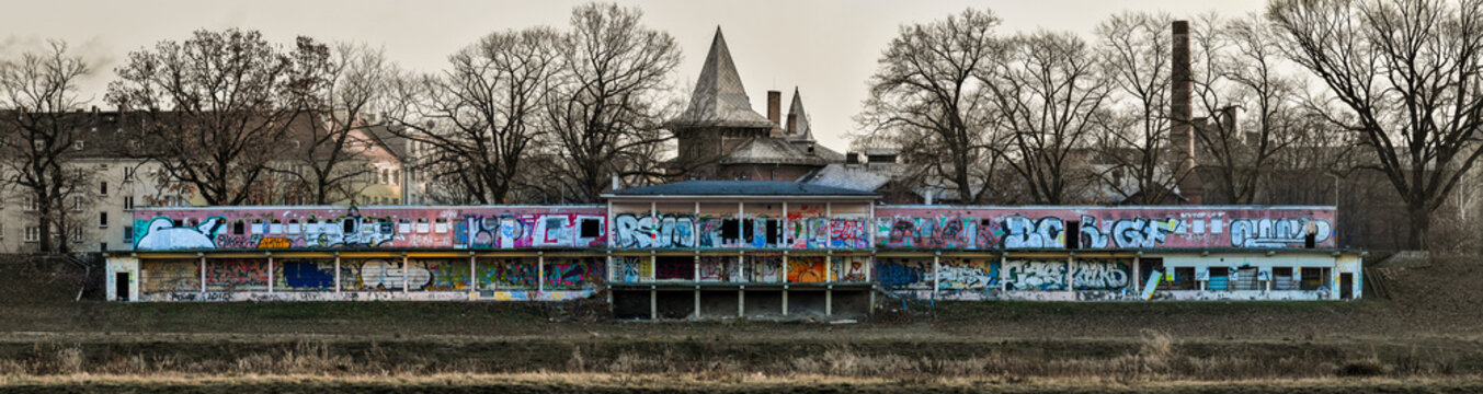 Old abandoned building on the banks of the river, painted with colorful graffiti.