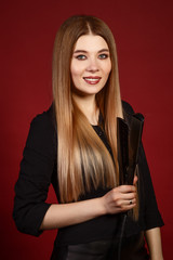 Woman hairstylist with curling iron on red background