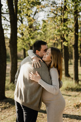 Fototapeta premium happy young pregnant couple walks in the park,husband holds the hand of his pregnant wife,future dad and mom,walks in the park after quarantine