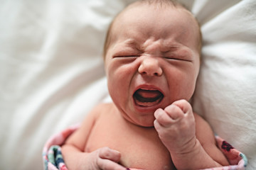 A cute Newborn baby crying in bed