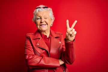 Senior beautiful grey-haired woman wearing casual red jacket and sunglasses smiling with happy face...
