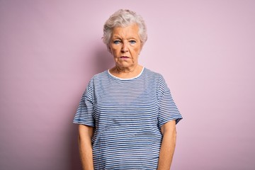 Senior beautiful grey-haired woman wearing casual t-shirt over isolated pink background with serious expression on face. Simple and natural looking at the camera.