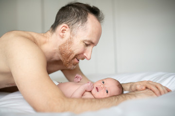 Obraz na płótnie Canvas A father with a newborn baby in bed