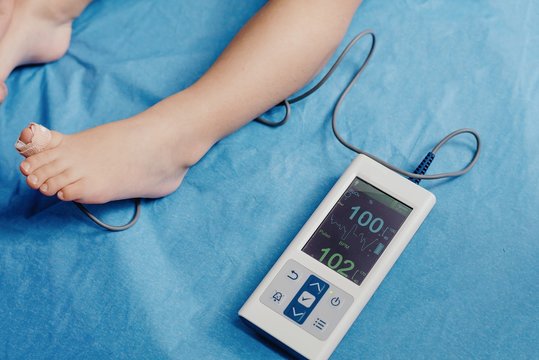 Doctor with oximeter examining little patient