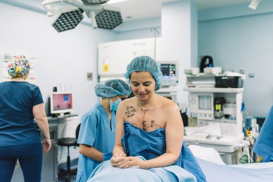 Blurred surgeon using photo camera to shoot breast of female patient before performing mammoplasty in modern hospital