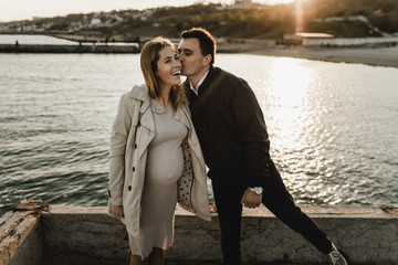 Young pregnant couple in love on summer sunny evening. at sunset on the beach,Beautiful young...