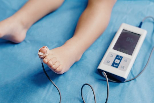 Doctor with oximeter examining little patient