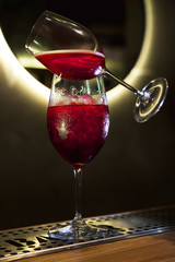 clover club alcoholic drink in a cocktail glass. 
Alcoholic red cocktail on a neon background in a bar. red cocktail with ice in a wine glass.Two wine glasses. splash of alcohol in motion