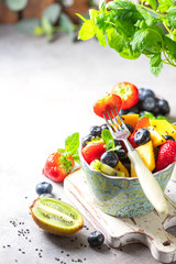 Fresh organic fruit salad on a light concrete background. Top view.