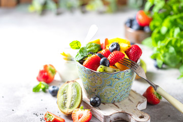 Fresh organic fruit salad on a light concrete background. Top view.
