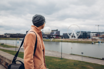 Young man tourist walking along pier by Wisla river in Krakow, Poland enjoying Ferris wheel landscape. Europe trip