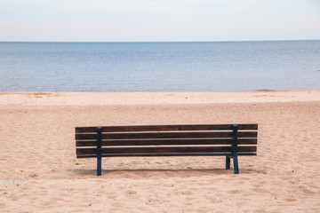 Naklejka na ściany i meble Lonely bench on the sandy seashore. Without people.